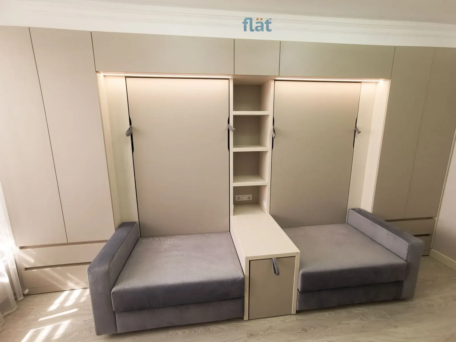 Two wall beds with armchairs and a shelving column between them